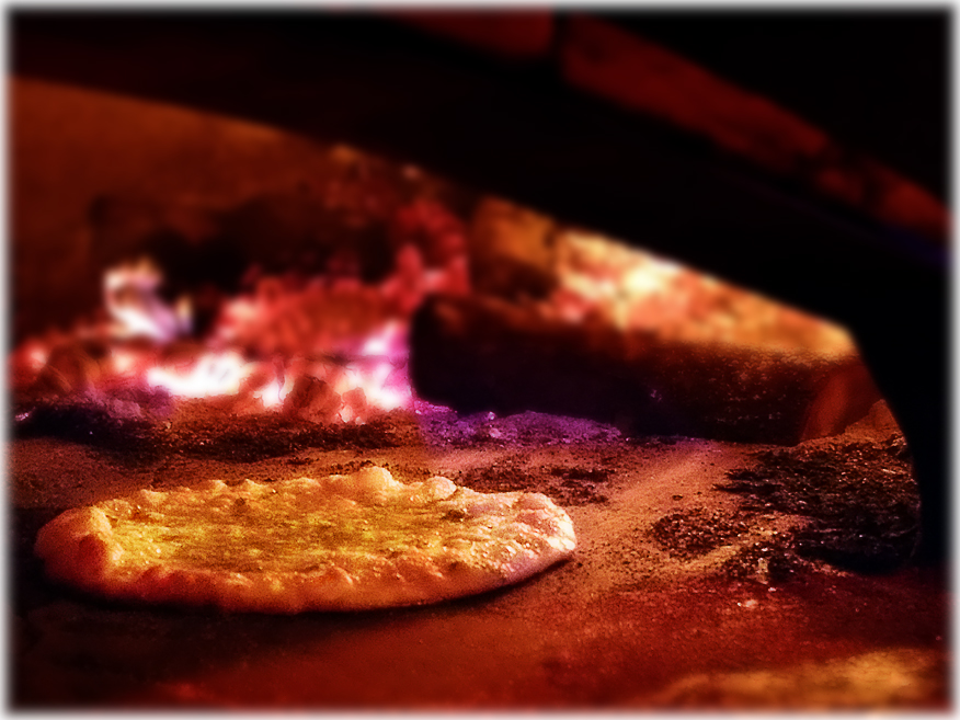Gourmet pizza cooking in wood fired oven